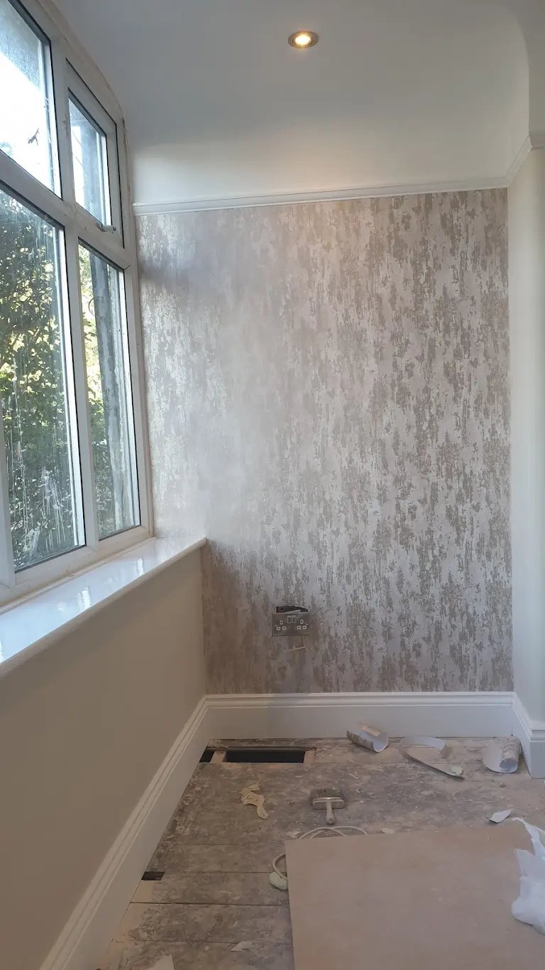 Feature wall hung with silver patterned wallpaper beside a bay window
