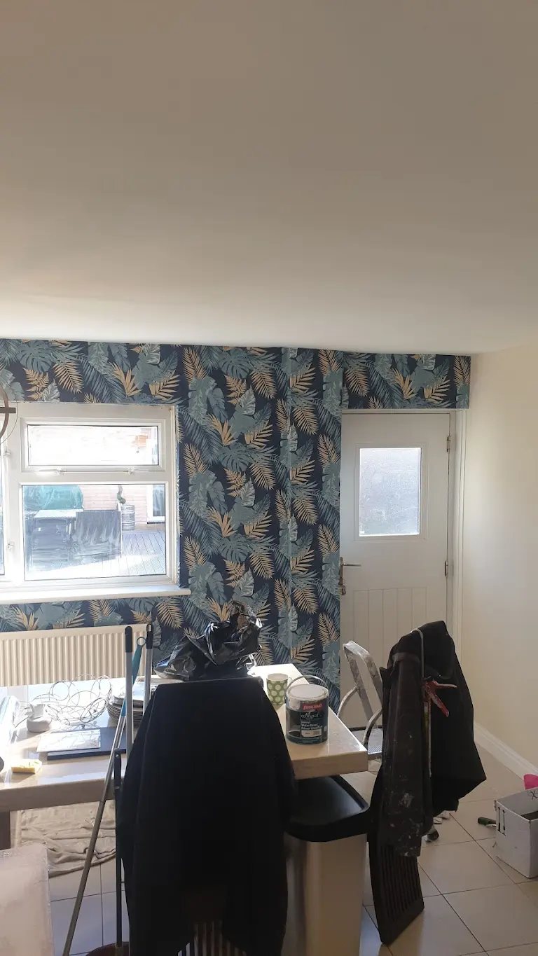 Kitchen diner with dark tropical leaf wallpaper on the end wall