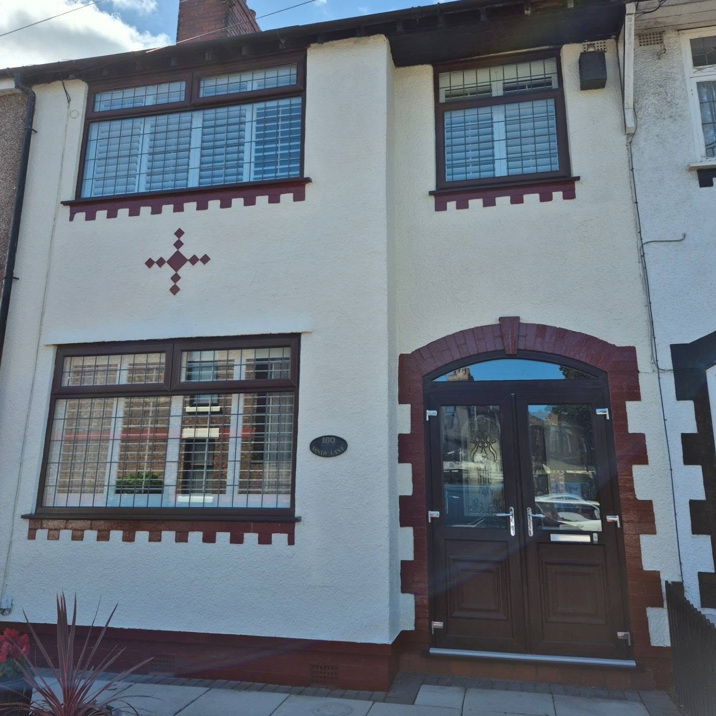 White painted house front with red brick details and dark window frames