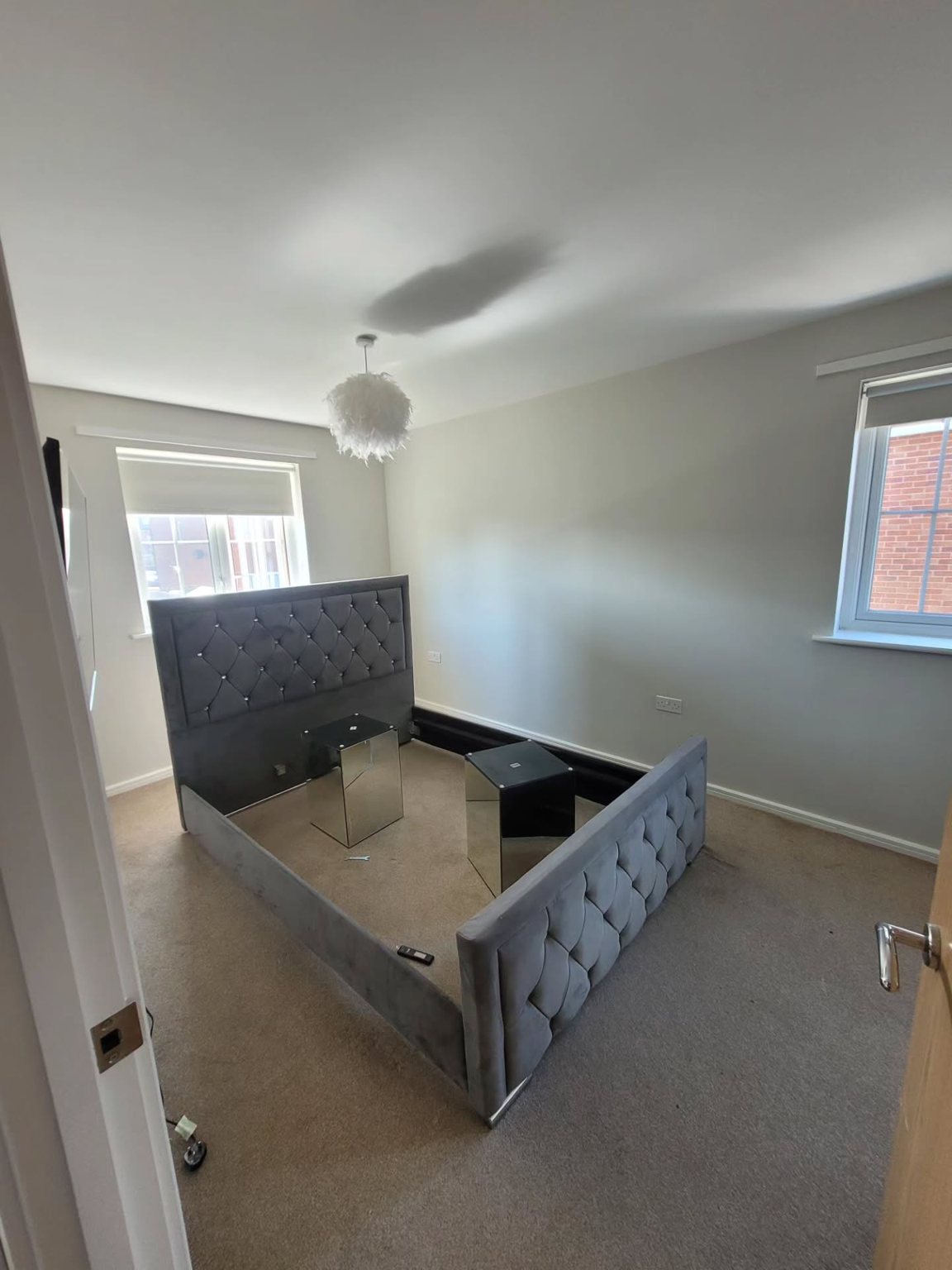 Freshly painted bedroom with grey carpet and upholstered bed frame